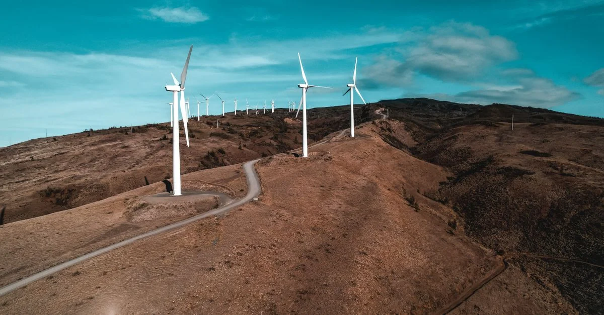 Une vue aérienne pittoresque montrant plusieurs éoliennes sur une colline sèche, mettant en avant l'énergie renouvelable.