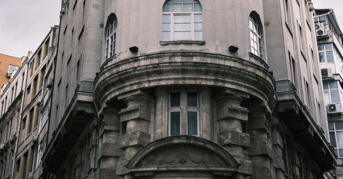Une vue détaillée d'un ancien bâtiment européen avec une architecture en pierre classique et des fenêtres en arc.