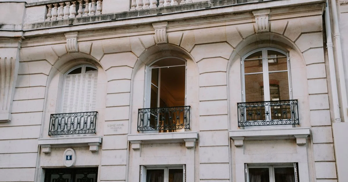 Une façade de bâtiment européen classique avec des fenêtres arquées et des balcons ornés.