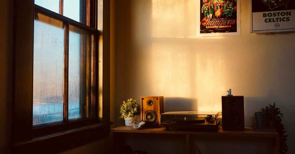 Une pièce à l'éclairage chaleureux, agrémentée d'enceintes vintage, d'une platine vinyle et d'affiches de basket-ball, créant une ambiance nostalgique.